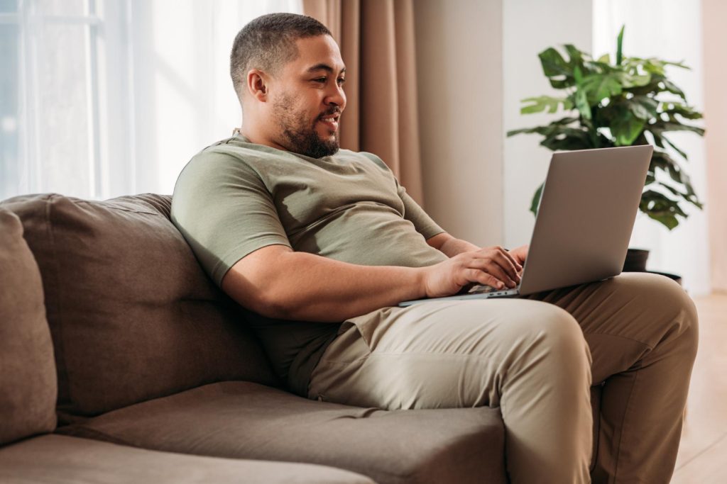 Homem usando notebook no sofá